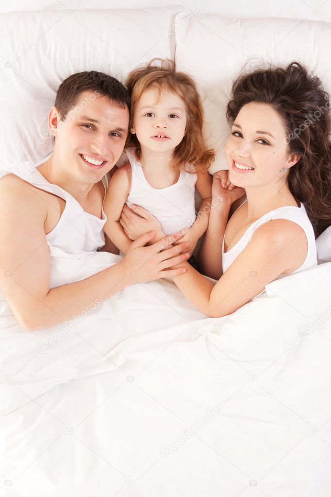 Happy family, mother, father and daughter resting on the white b