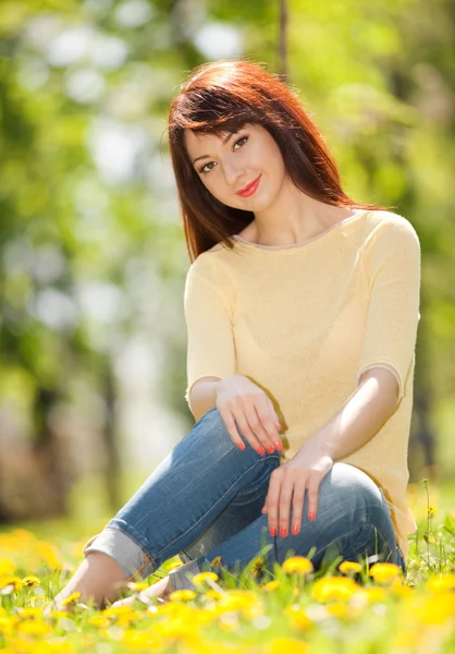 Mujer joven en el parque con flores — Foto de Stock