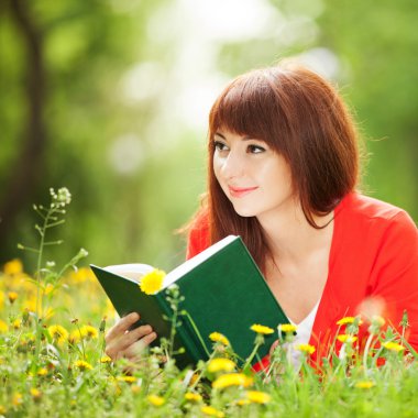 genç kadın çiçeklerle parkta bir kitap okuma