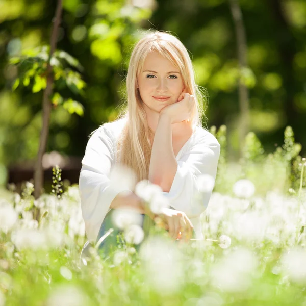 Carino riposo donna nel parco con denti di leone — Foto Stock