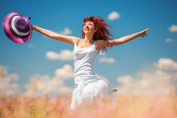 Nette Frau läuft mit Blumen über das Feld — Stockfoto