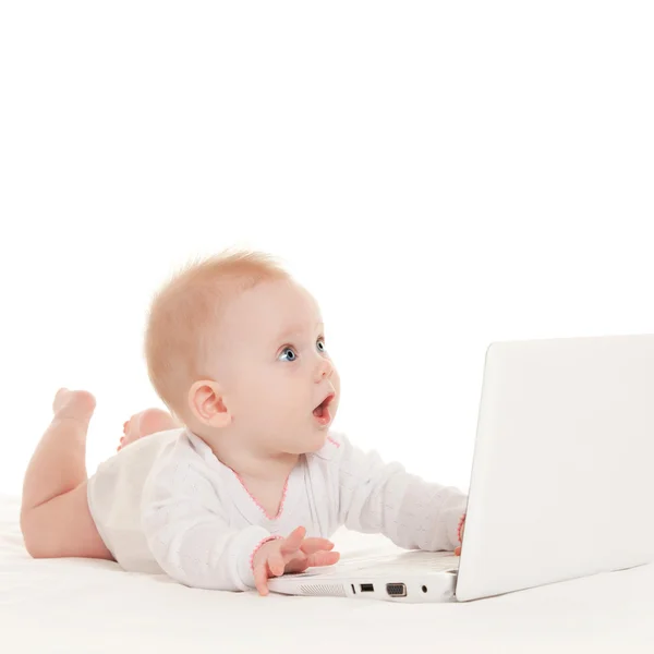 Leuke baby met laptop op het witte bed — Stockfoto