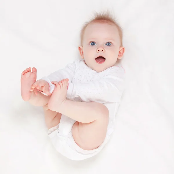 Słodkie dziecko z pięknymi niebieskimi oczami leżące w białym łóżku — Zdjęcie stockowe
