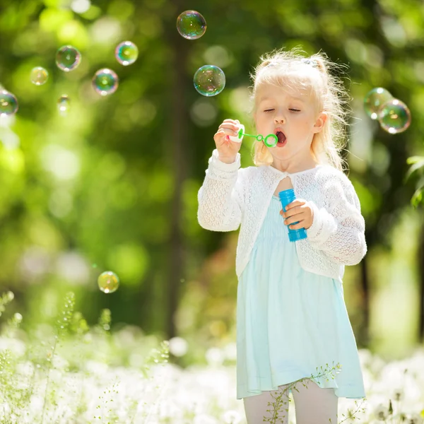 Cute little girl blowing bubbles in the park — Stock Photo, Image