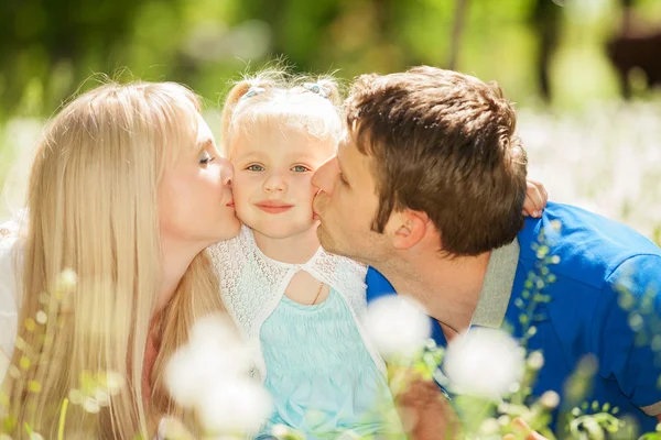 Happy matka a otec líbat jejich dcera v parku — Stock fotografie