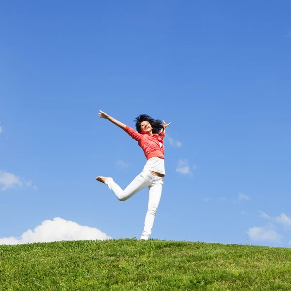 Hübsche junge Frau springt auf grünem Gras — Stockfoto