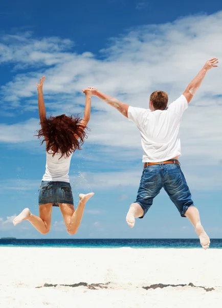 幸せなカップル、ビーチ上にジャンプ — ストック写真
