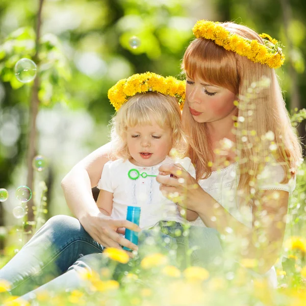 Lycklig mor och dotter blåser bubblor i parken — Stockfoto