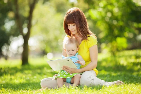 Familia feliz, madre e hija con la tableta descansando a la par — Foto de Stock