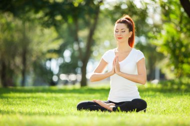 Parkta yoga egzersizi yapan güzel bir kadın.