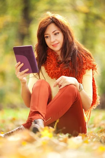 Mujer bonita joven con la tableta en el parque de otoño — Foto de Stock