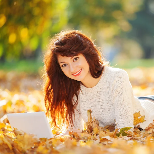 Linda mujer con portátil blanco en el parque otoño — Stockfoto