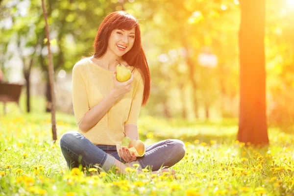 Glückliche Frau isst Früchte im Park — Stockfoto