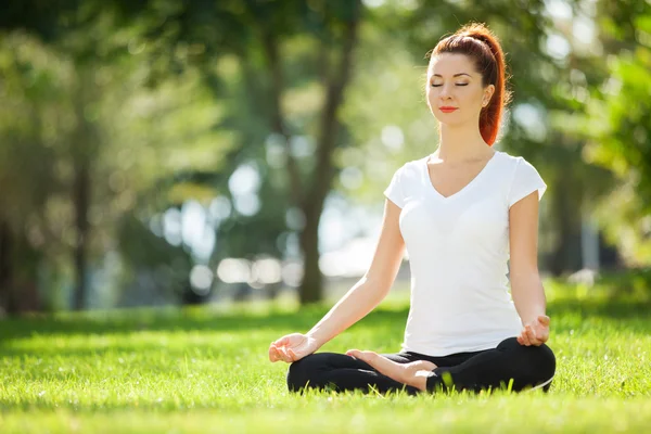 Parkta yoga egzersizi yapan güzel bir kadın. — Stok fotoğraf