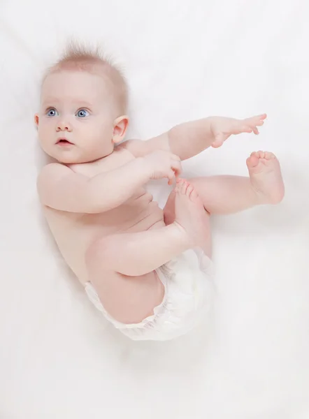 Χαριτωμένο μωρό με όμορφα μπλε μάτια ξαπλωμένο σε λευκό κρεβάτι — Φωτογραφία Αρχείου