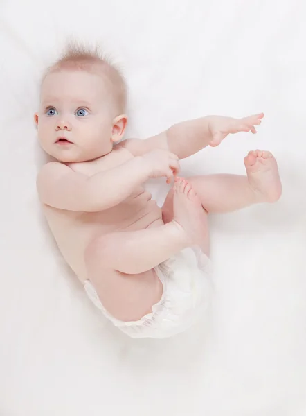 Bebê bonito com belos olhos azuis deitado na cama branca — Fotografia de Stock