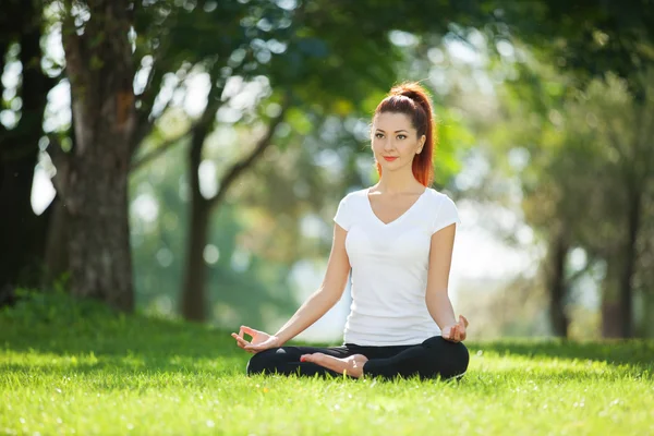 Parkta yoga egzersizi yapan güzel bir kadın. — Stok fotoğraf