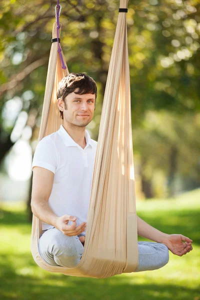 Anti-gravity joga, człowiek robi ćwiczenia jogi w parku — Zdjęcie stockowe