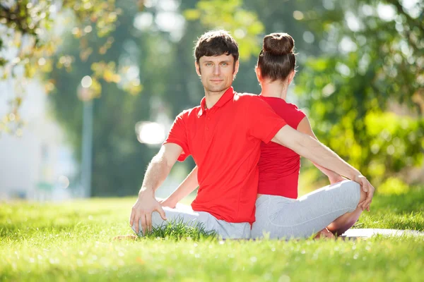 Parejas Yoga, hombre y mujer haciendo ejercicios de yoga en el parque — Foto de Stock