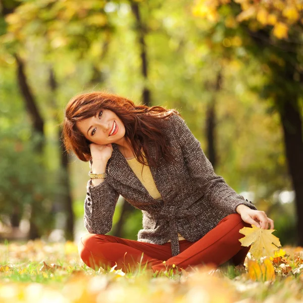 Nuori kaunis nainen rentouttava syksyllä puistossa — kuvapankkivalokuva