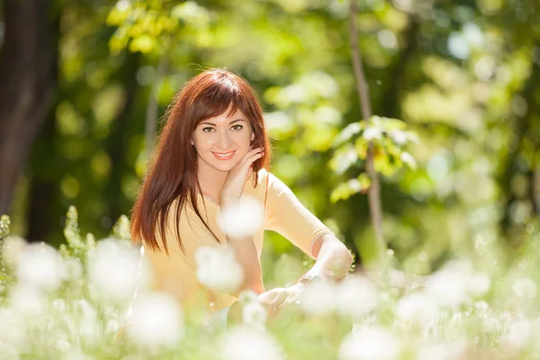 Carino riposo donna nel parco con denti di leone — Foto Stock