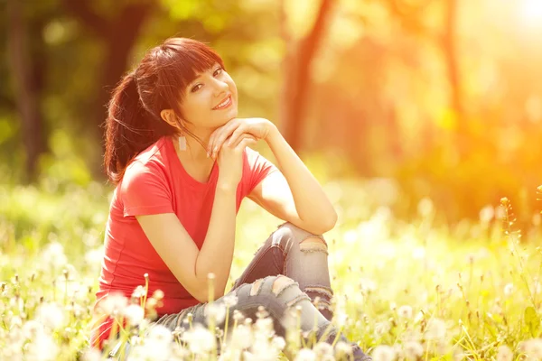 Leuke vrouw in het park met paardebloemen — Stockfoto