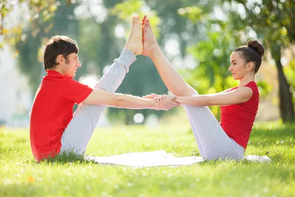 Couples Yoga, homme et femme faisant des exercices de yoga dans le parc — Photo