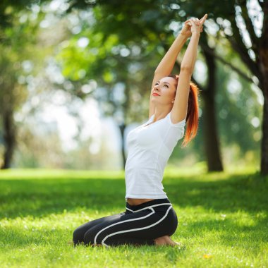 Parkta yoga egzersizi yapan güzel bir kadın.