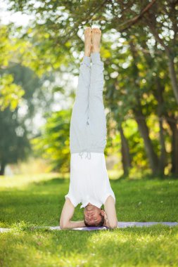 Adam parkta yoga egzersizleri yapıyor.