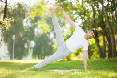 Adam parkta yoga egzersizleri yapıyor.