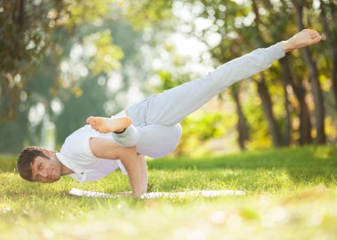 Adam parkta yoga egzersizleri yapıyor.