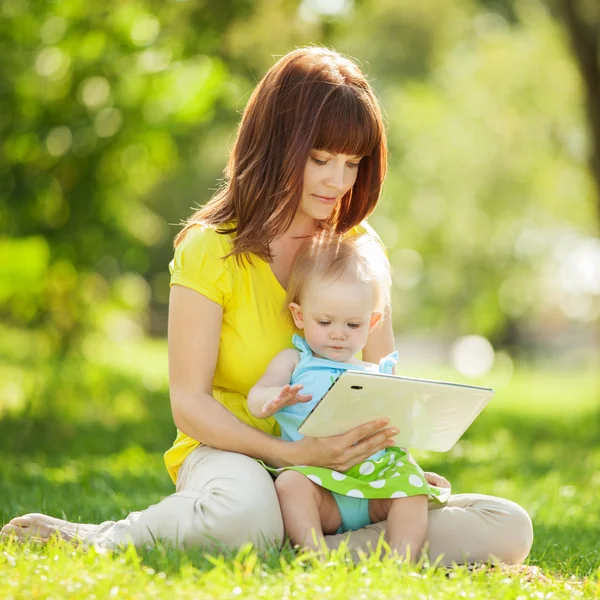 Familia feliz, madre e hija con la tableta descansando a la par — Foto de Stock