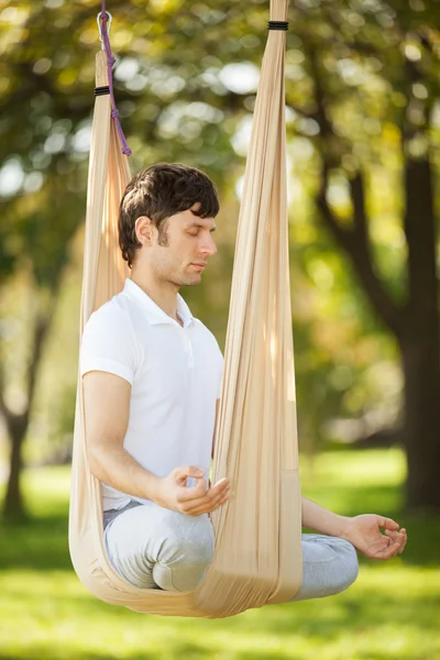 Anti-gravity joga, człowiek robi ćwiczenia jogi w parku — Zdjęcie stockowe