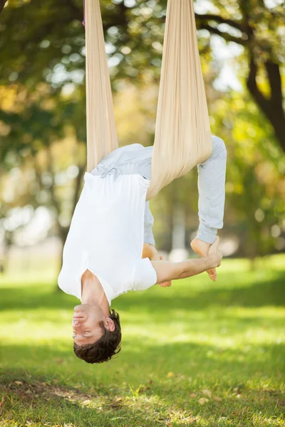 Antigravitační jóga, člověk dělá cvičení jógy v parku — Stock fotografie