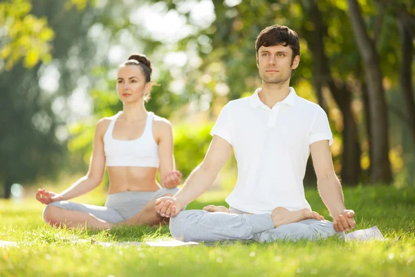 Couples Yoga, homme et femme faisant des exercices de yoga dans le parc — Photo