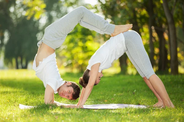 Pareja de Yoga, hombre y mujer haciendo ejercicios de yoga en el parque —  Fotos de Stock