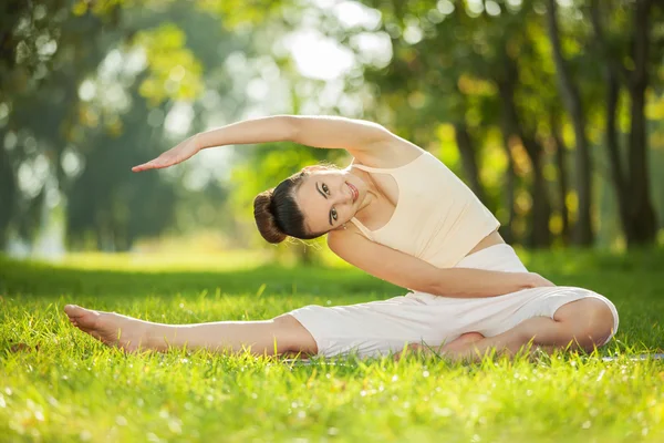 Vacker kvinna gör yogaövningar i parken — Stockfoto