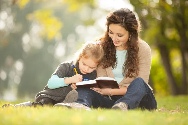 Mutter mit Tochter liest im Park ein Buch — Stockfoto