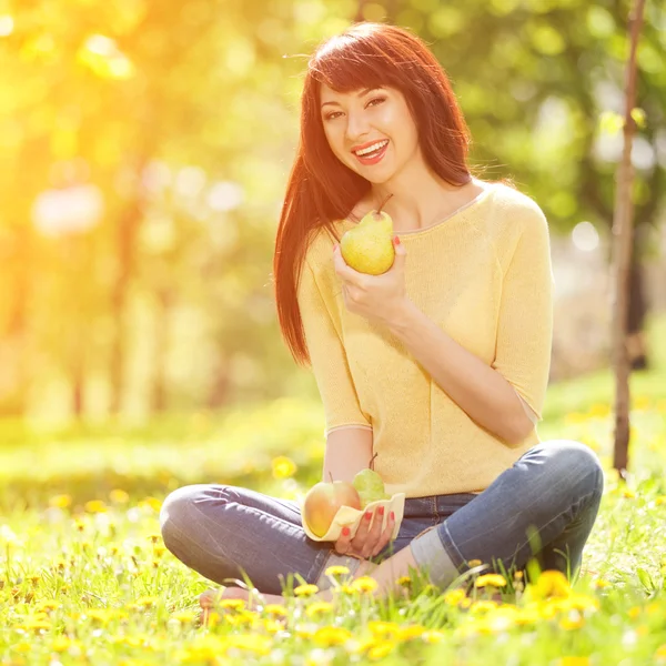 Szczęśliwa kobieta jedzenie owoców w parku — Zdjęcie stockowe
