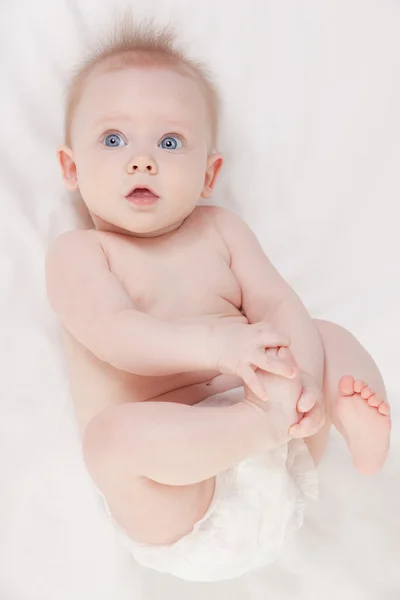 Bebê bonito com belos olhos azuis deitado na cama branca — Fotografia de Stock