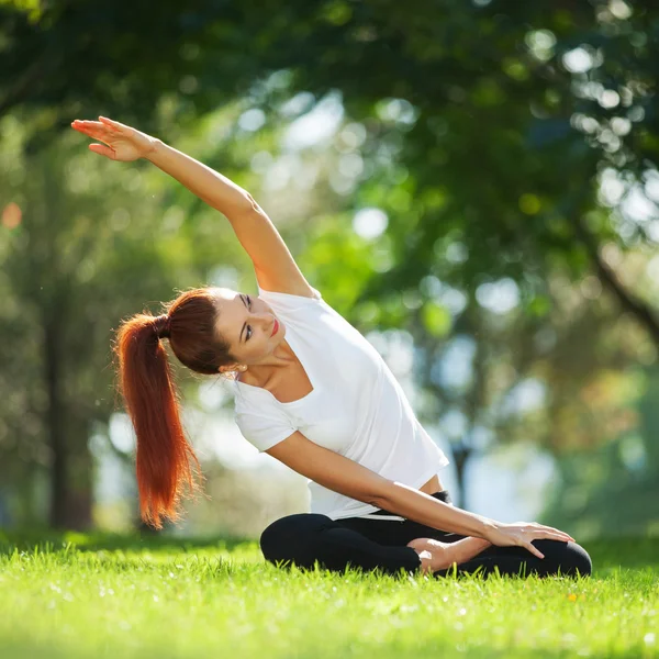 Parkta yoga egzersizi yapan güzel bir kadın. — Stok fotoğraf