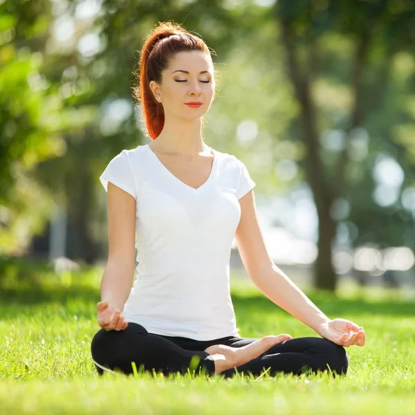 Pretty woman doing yoga exercises in the park — Stock Photo, Image