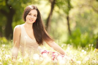 Şirin bir kadın parkta karahindiba ile dinleniyor.