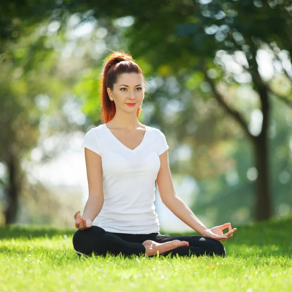 Parkta yoga egzersizi yapan güzel bir kadın. — Stok fotoğraf