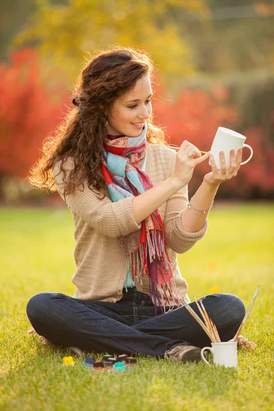 Красивая женщина рисует чашки в парке — стоковое фото