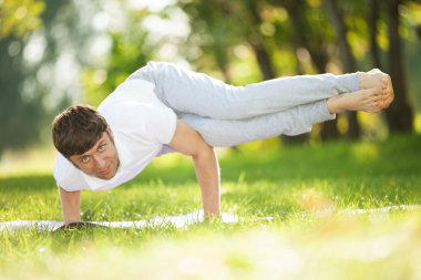 Adam parkta yoga egzersizleri yapıyor.