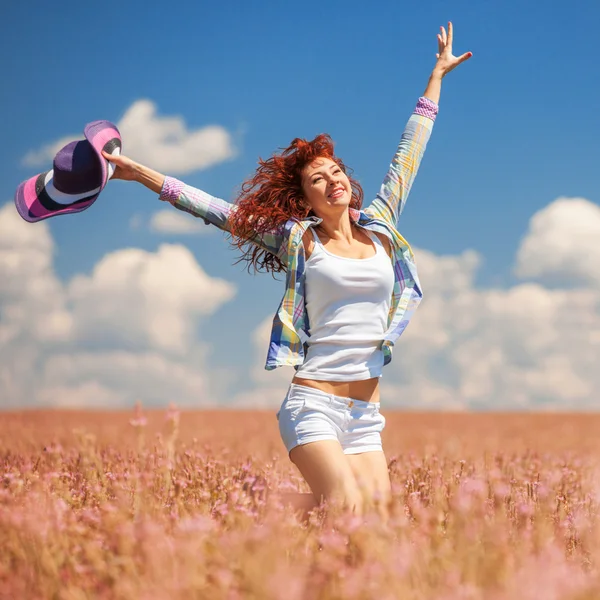 Nette Frau läuft mit Blumen über das Feld — Stockfoto