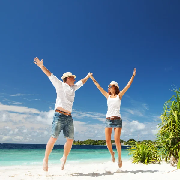 Happy couple jumping on the tropical beach — Stock Photo, Image