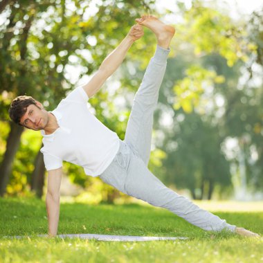 Adam parkta yoga egzersizleri yapıyor.