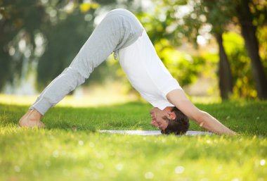 Adam parkta yoga egzersizleri yapıyor.